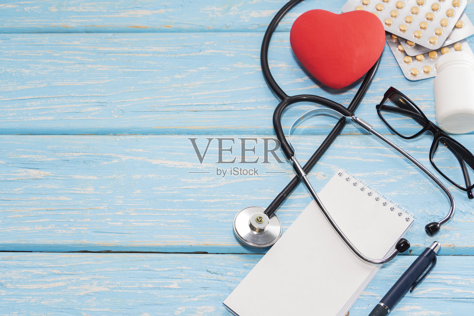 一颗带听诊器的心脏躺在一个轻木制的背景上。健康的心脏照片摄影图片