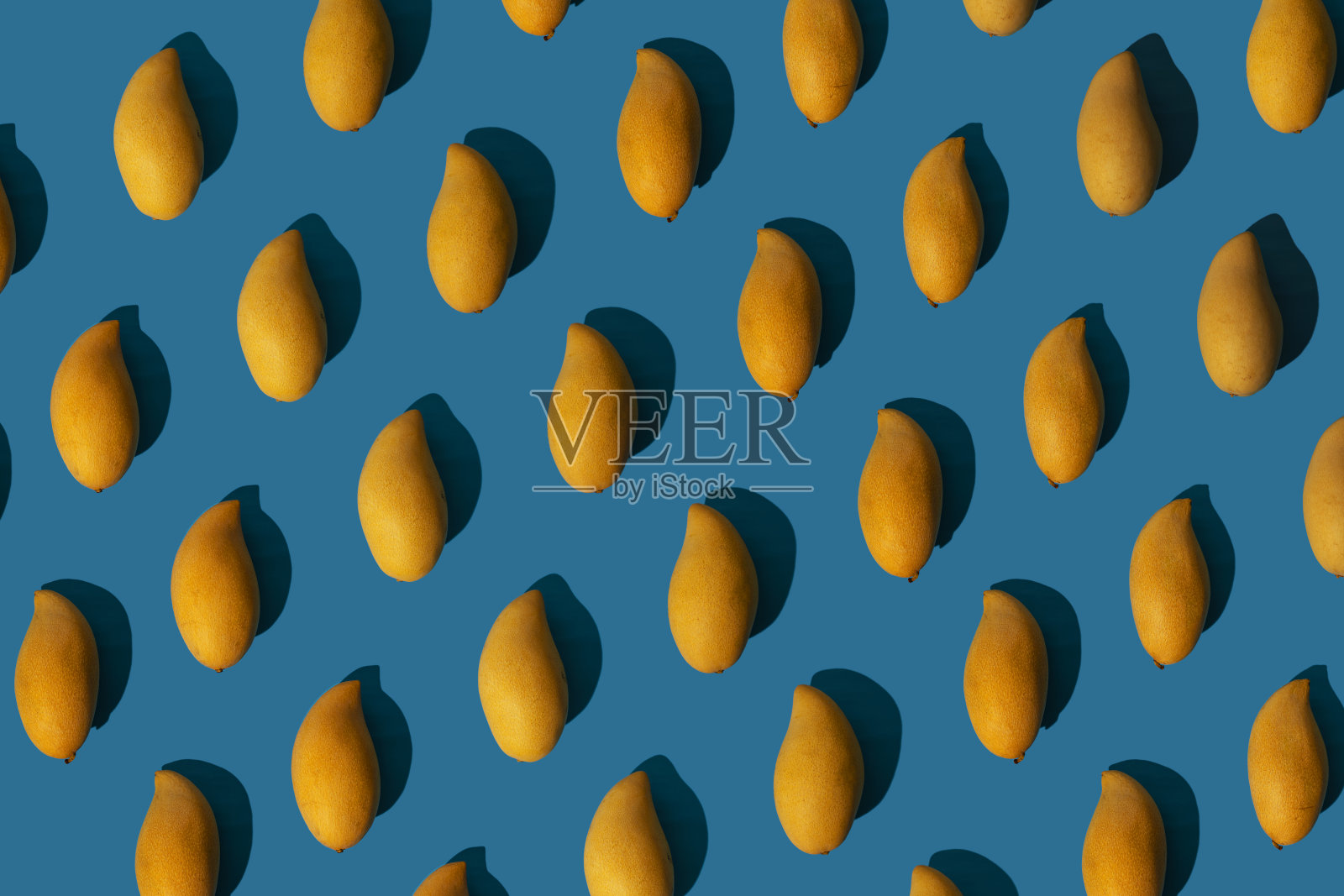 时髦的阳光夏天模式与黄色芒果在明亮的浅蓝色背景。最小的夏天的概念。照片摄影图片