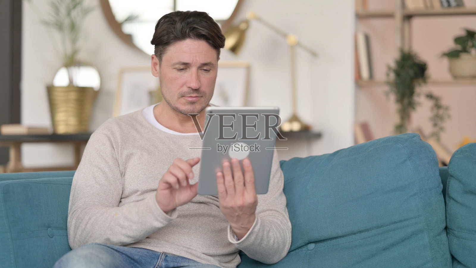 迷人的中年男子使用平板电脑,在家里照片摄影图片