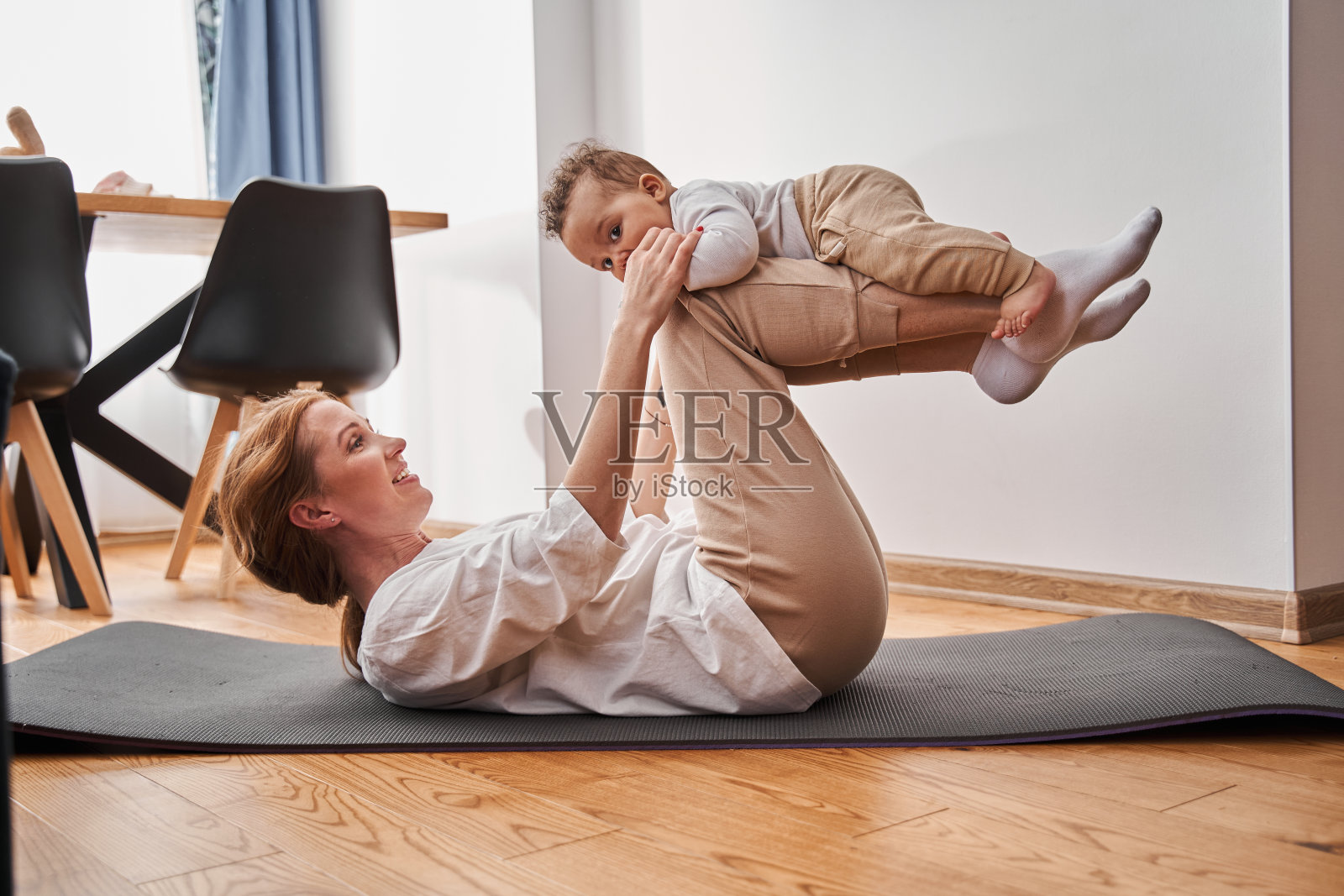 一位穿着家服的妇女躺在后面,儿子躺在她的膝盖上照片摄影图片
