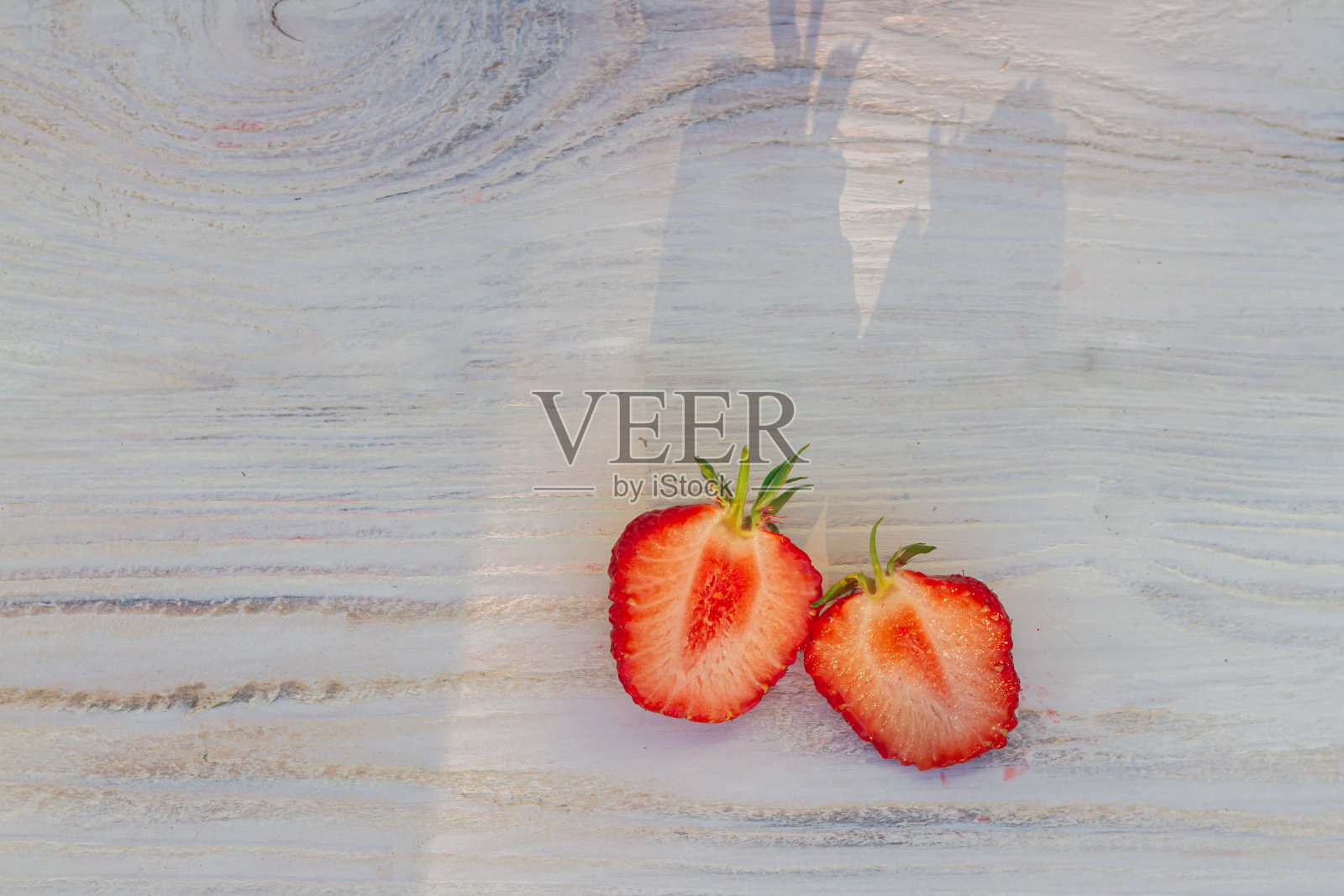 将切成两半的整个草莓放在白色的木质背景上照片摄影图片