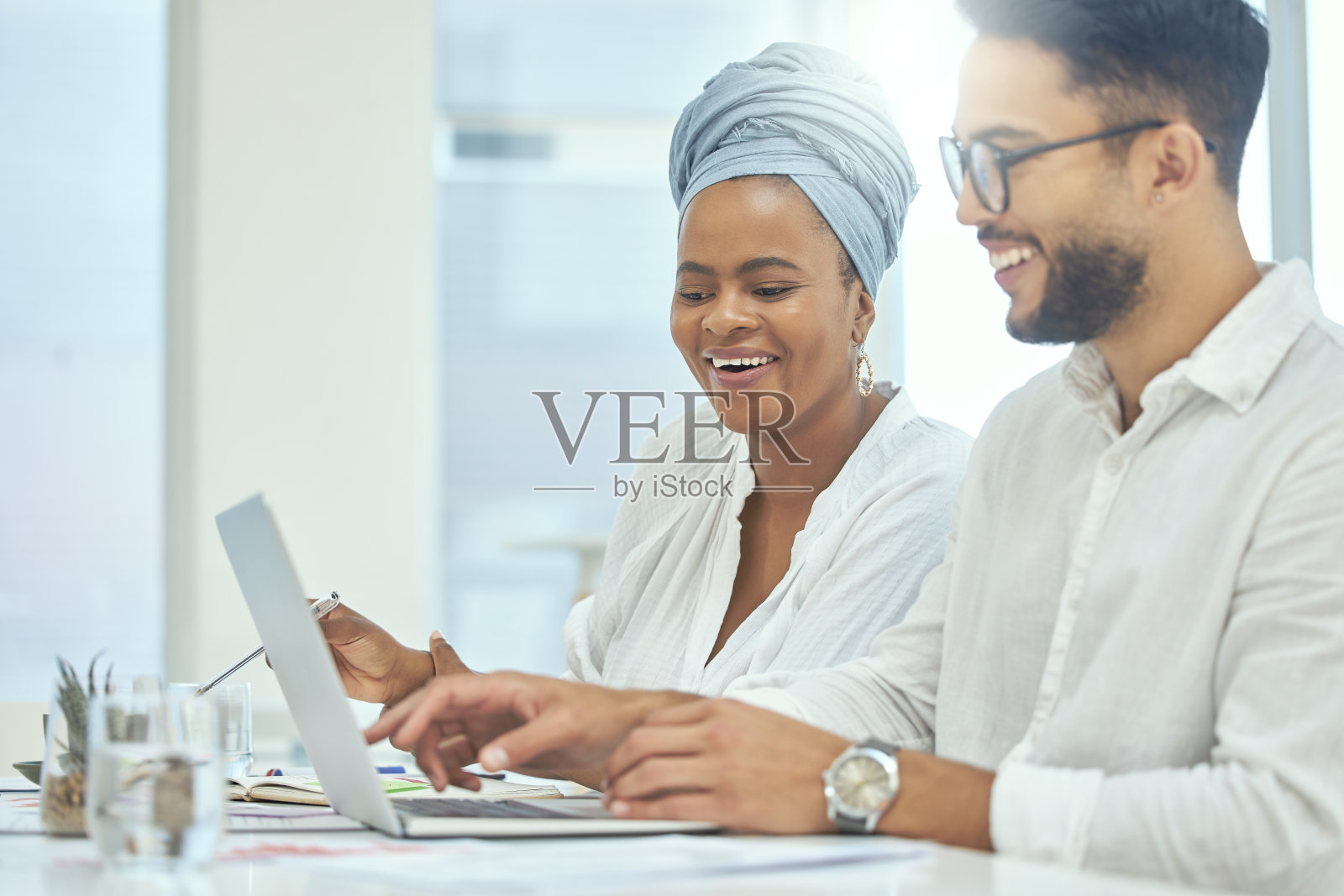 这是两名年轻的商人在办公室用笔记本电脑一起工作的镜头照片摄影图片