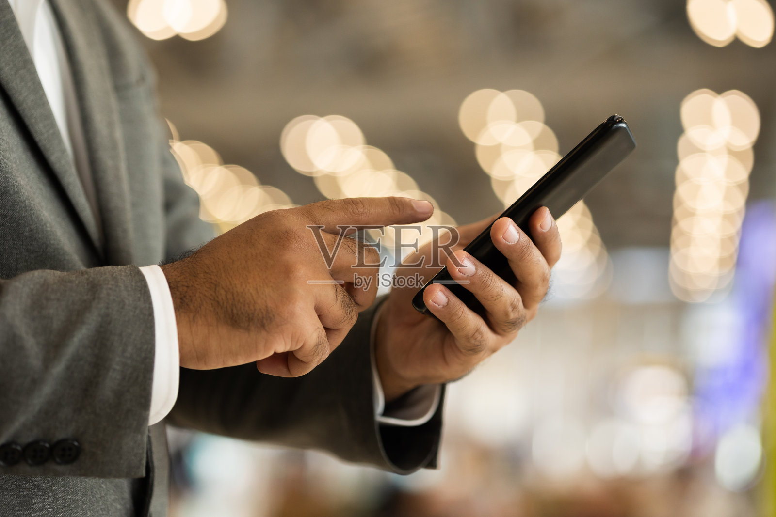 近距离观察手持智能手机的商人。他站在机场终点站。用手机办理登机手续。照片摄影图片