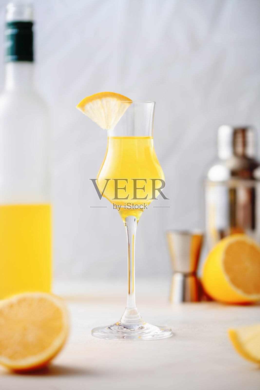 玻璃杯中的柠檬酒,甜甜的意大利柠檬利口酒,传统的烈性酒精饮料和柠檬在蓝色的背景。照片摄影图片