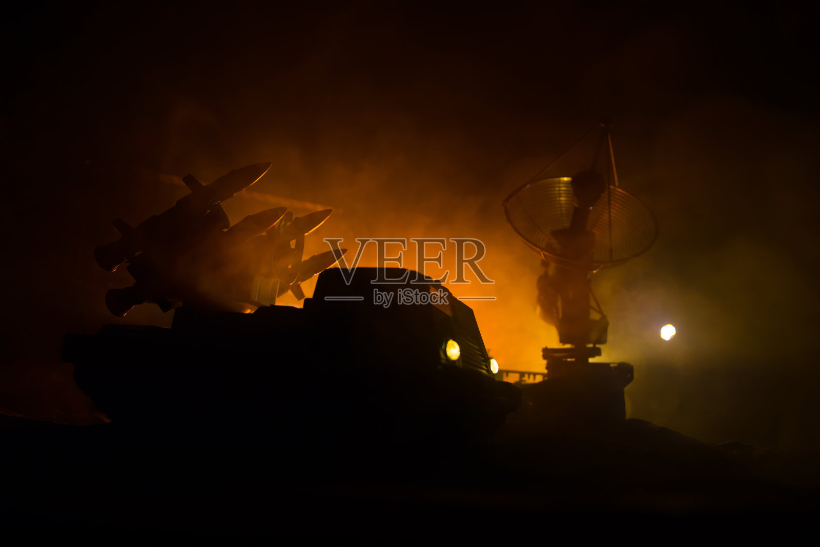 创意艺术品装饰。日落时分,装有雷达天线的机动防空卡车的剪影。卫星天线或无线电天线对着夜空。照片摄影图片