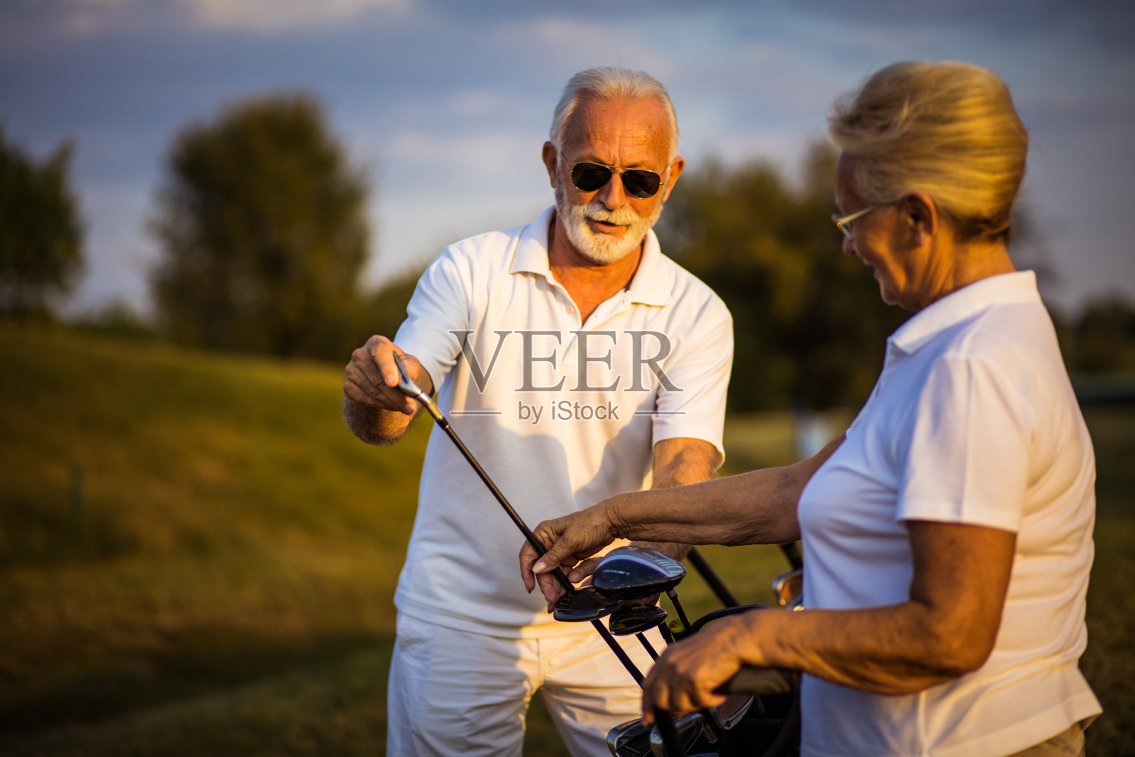 老高尔夫球手在球场上交谈。照片摄影图片