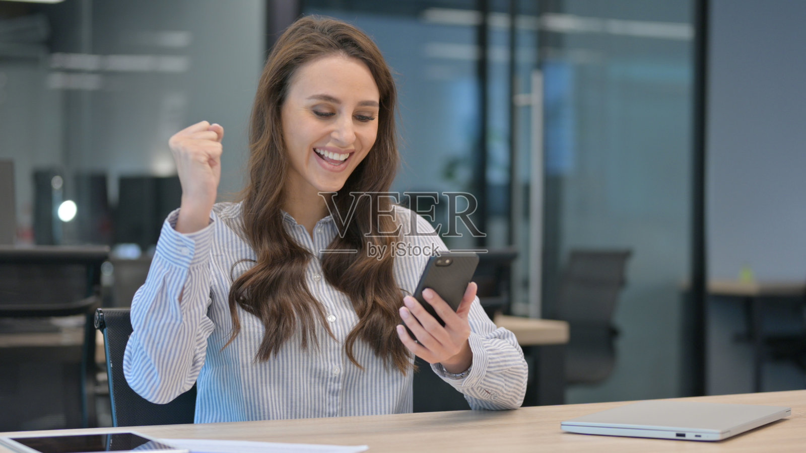 成功的年轻女商人在智能手机上庆祝照片摄影图片