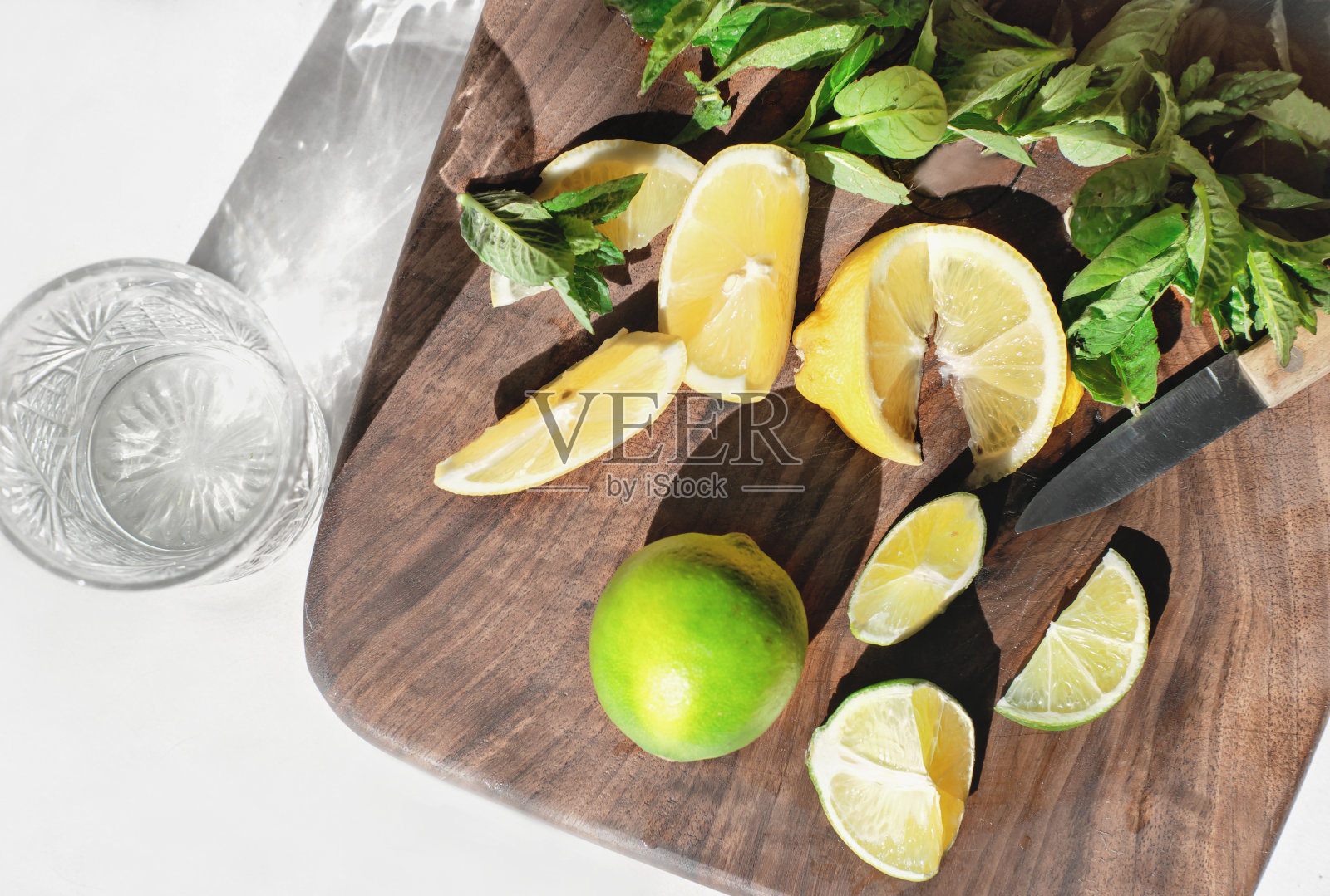 准备自制莫吉托柠檬水。把柠檬片、酸橙片和新鲜薄荷叶放在砧板上。夏季排毒饮料。照片摄影图片