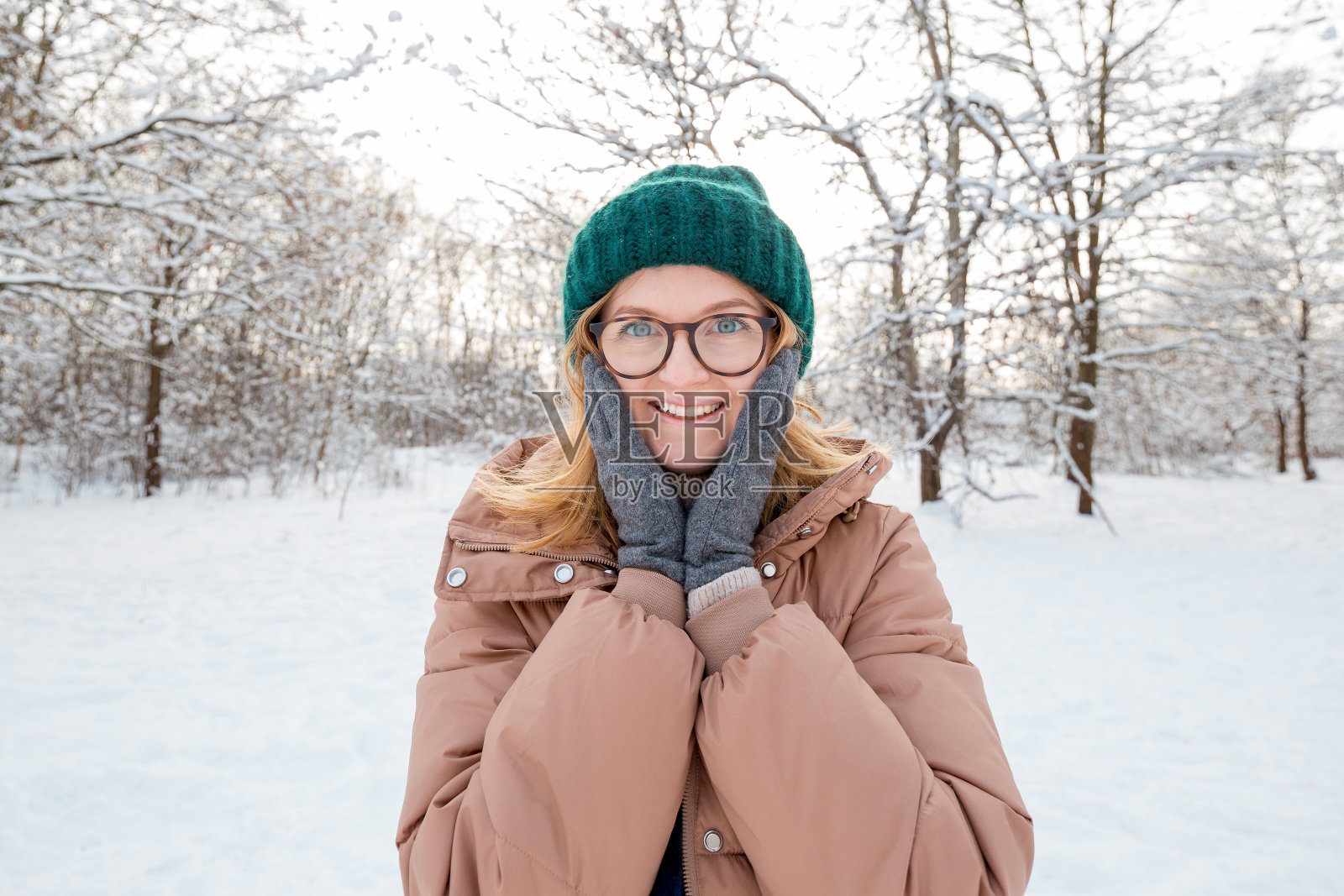 快乐的年轻女子戴着冬季针织帽在自然背景下摆姿势,看着相机和微笑。旅行和积极的生活理念。在户外照片摄影图片