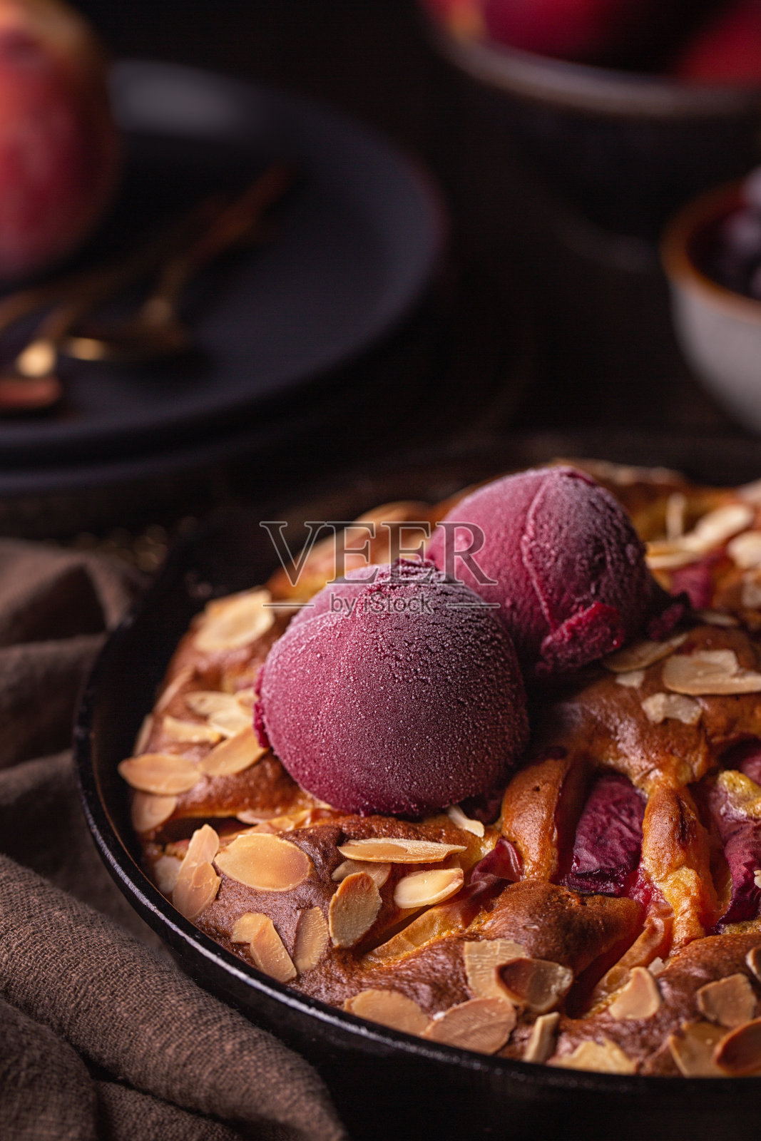 特写的浆果冰沙上的水果蛋糕与桃子,浆果和杏仁。黑暗情绪的照片。垂直的图像。照片摄影图片