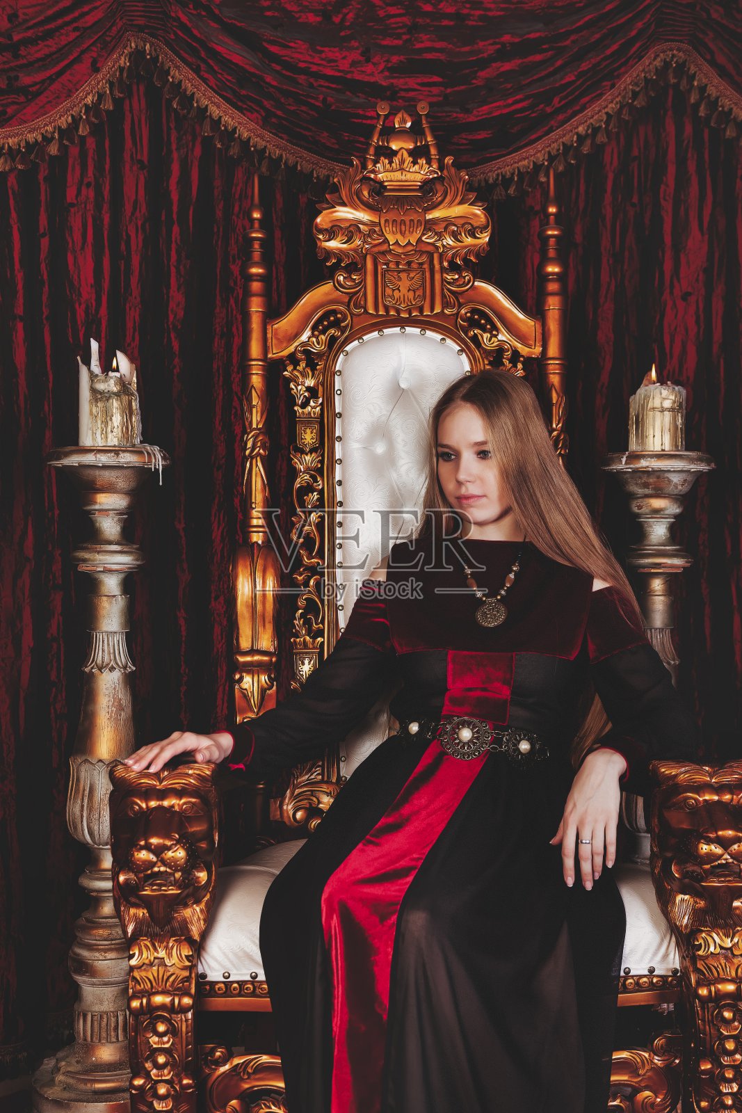 中世纪女王穿着历史服装,坐在城堡里的金色宝座上照片摄影图片