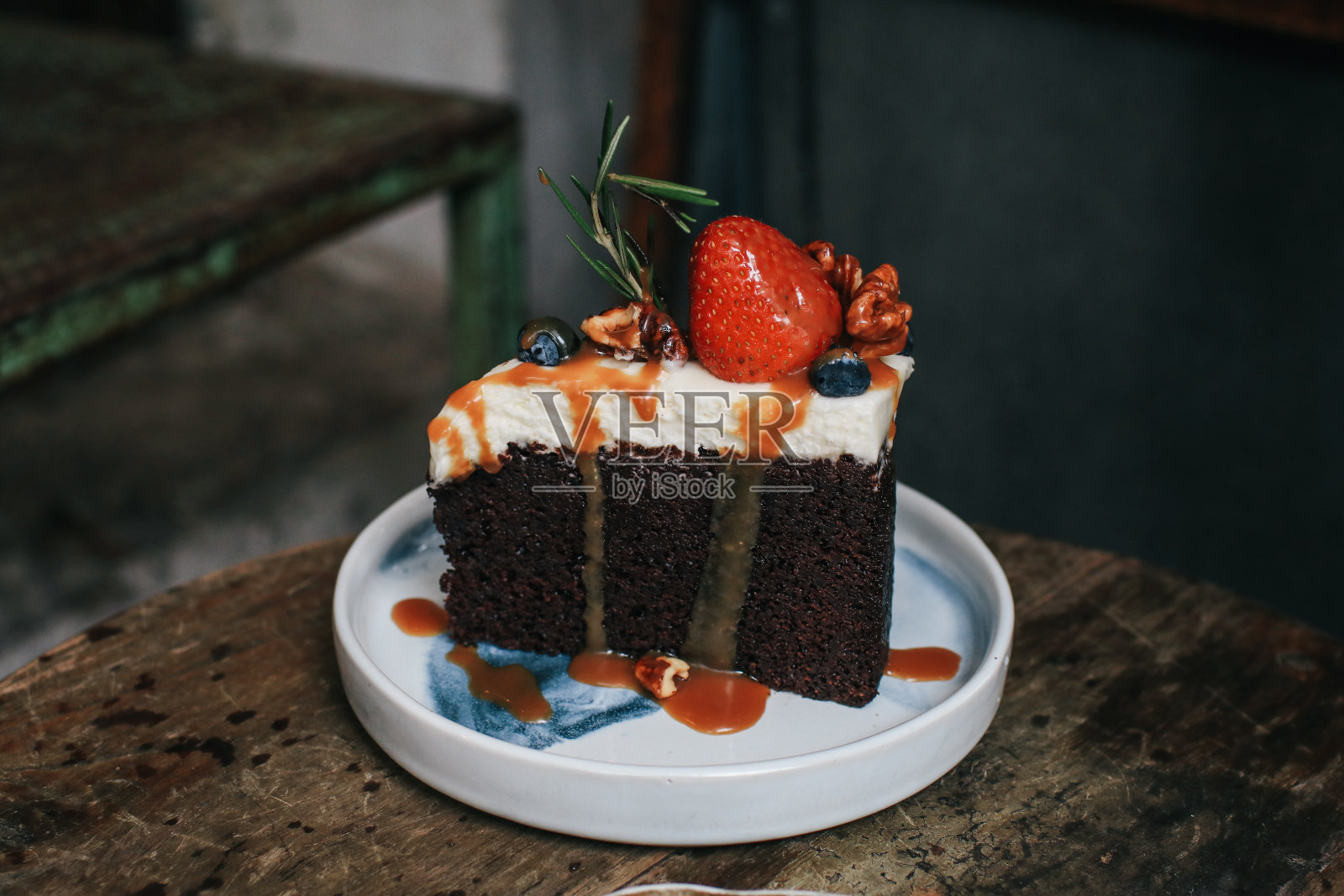 白色盘子上的黑啤酒巧克力蛋糕,木桌上装饰着草莓、蓝莓和开心果。照片摄影图片