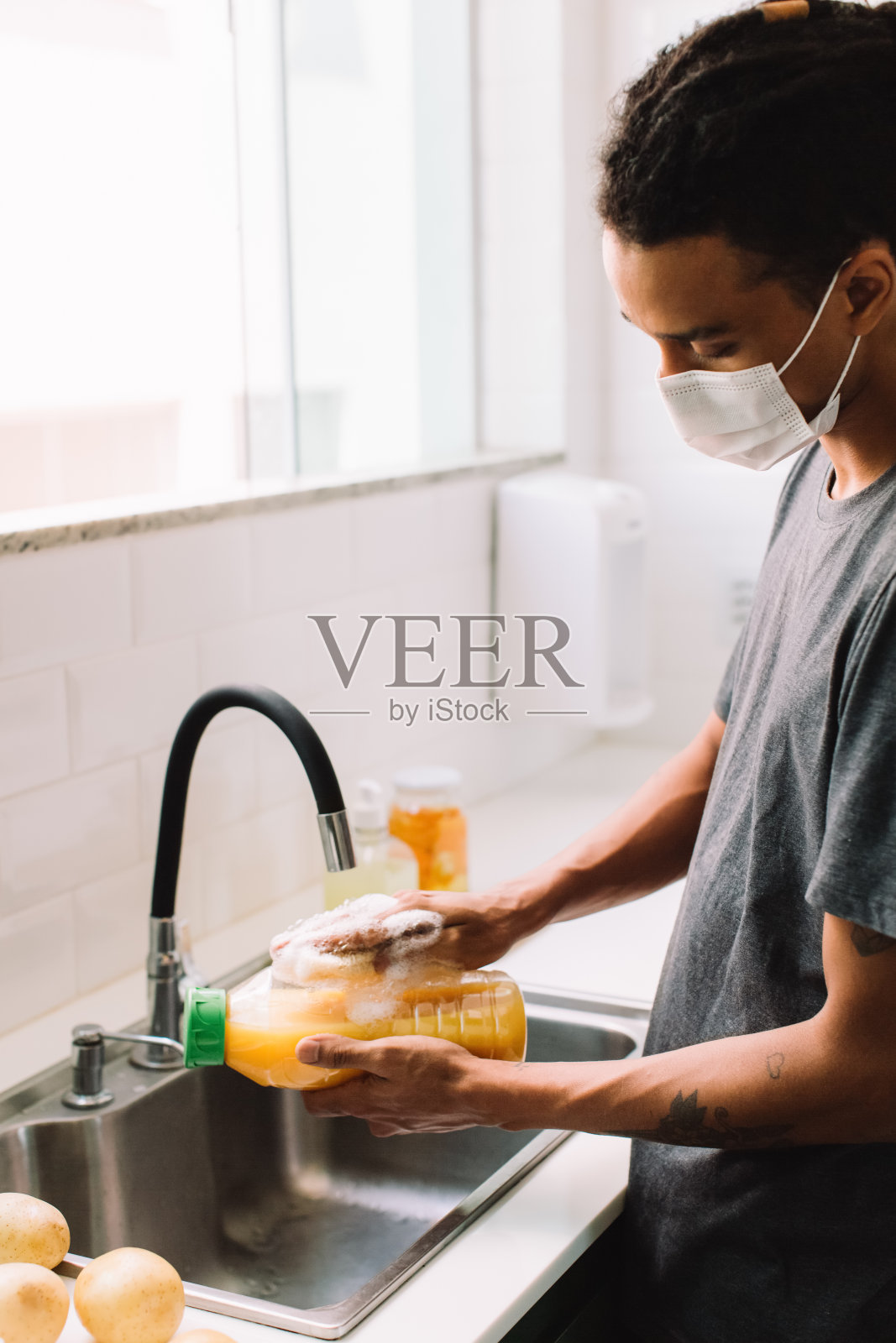 一名年轻人在冠状病毒大流行期间用消毒肥皂清洗食品杂货照片摄影图片