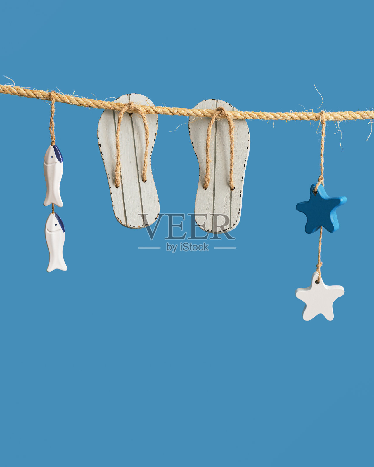航海概念与海上生活方式的装饰挂在绳索上。海玩具人字拖,海星和小鱼照片摄影图片