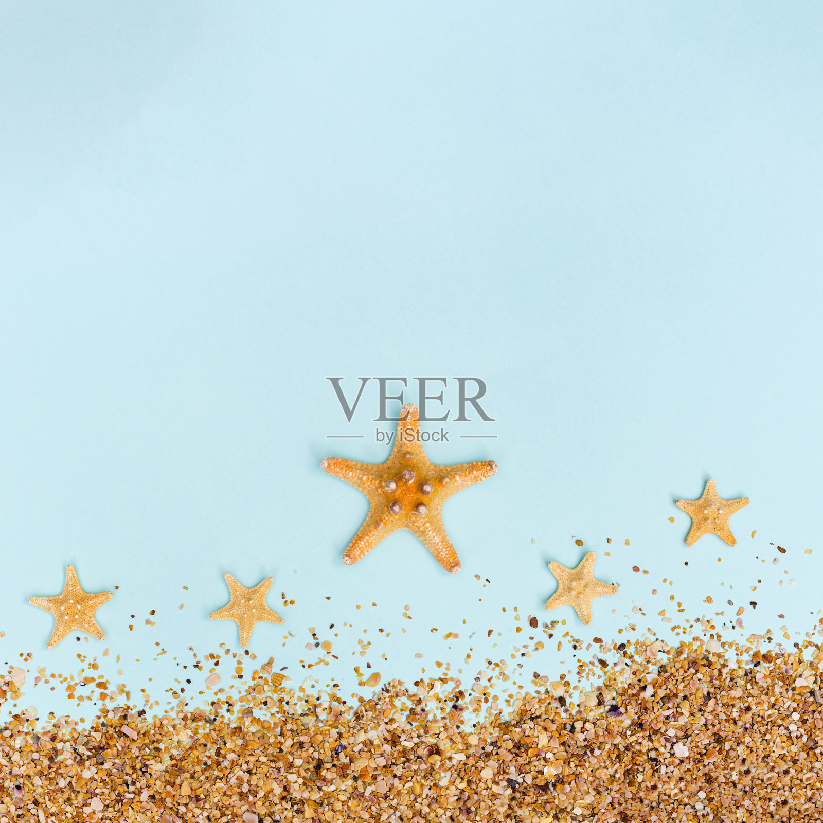 夏季背景与黄色海星和沙在柔和的蓝色。旅行和度假的概念。照片摄影图片