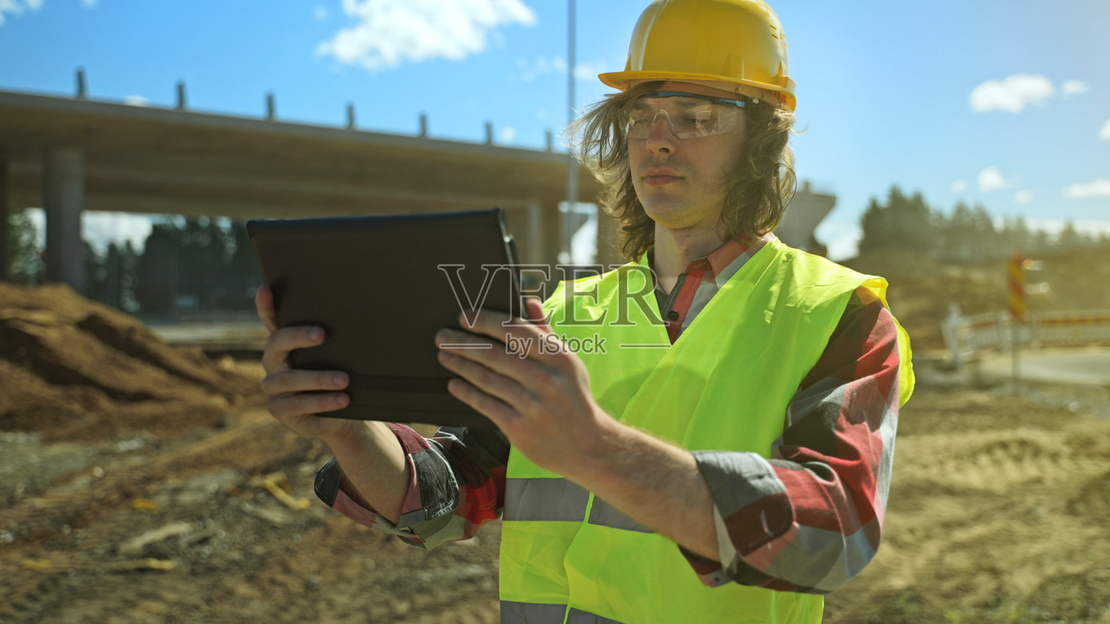 建设者与平板电脑在道路路口工地。照片摄影图片