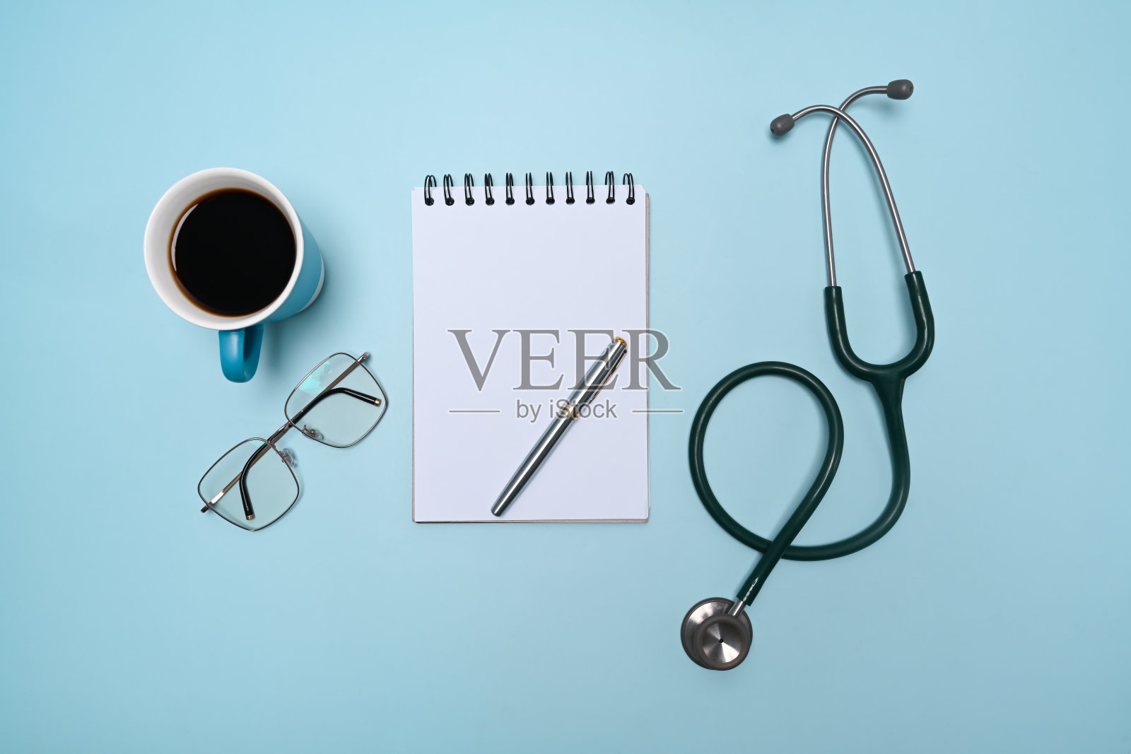 空记事本,听诊器,眼镜和咖啡杯在蓝色背景。照片摄影图片