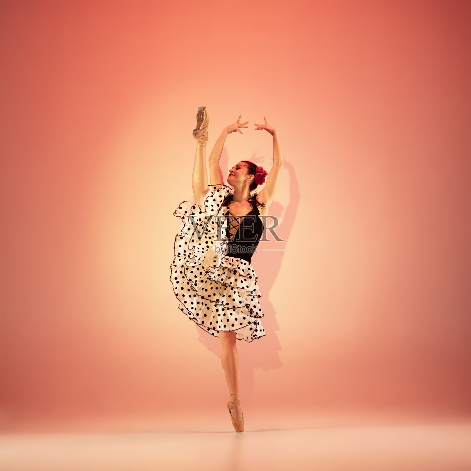 年轻美丽的芭蕾舞演员在充满灯光的红色演播室里摆姿势跳舞。照片摄影图片