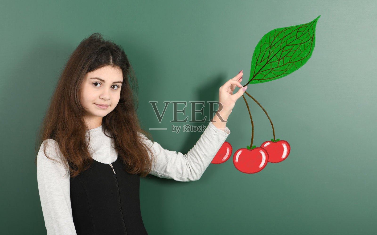 青春期前的女孩拿着画好的红樱桃照片摄影图片