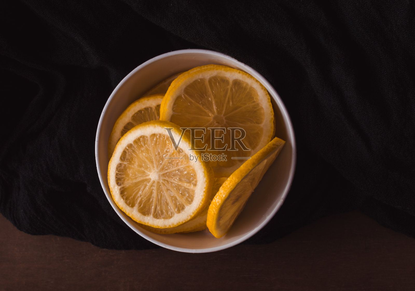 柠檬片在白色碗与黑色图案的背景照片摄影图片