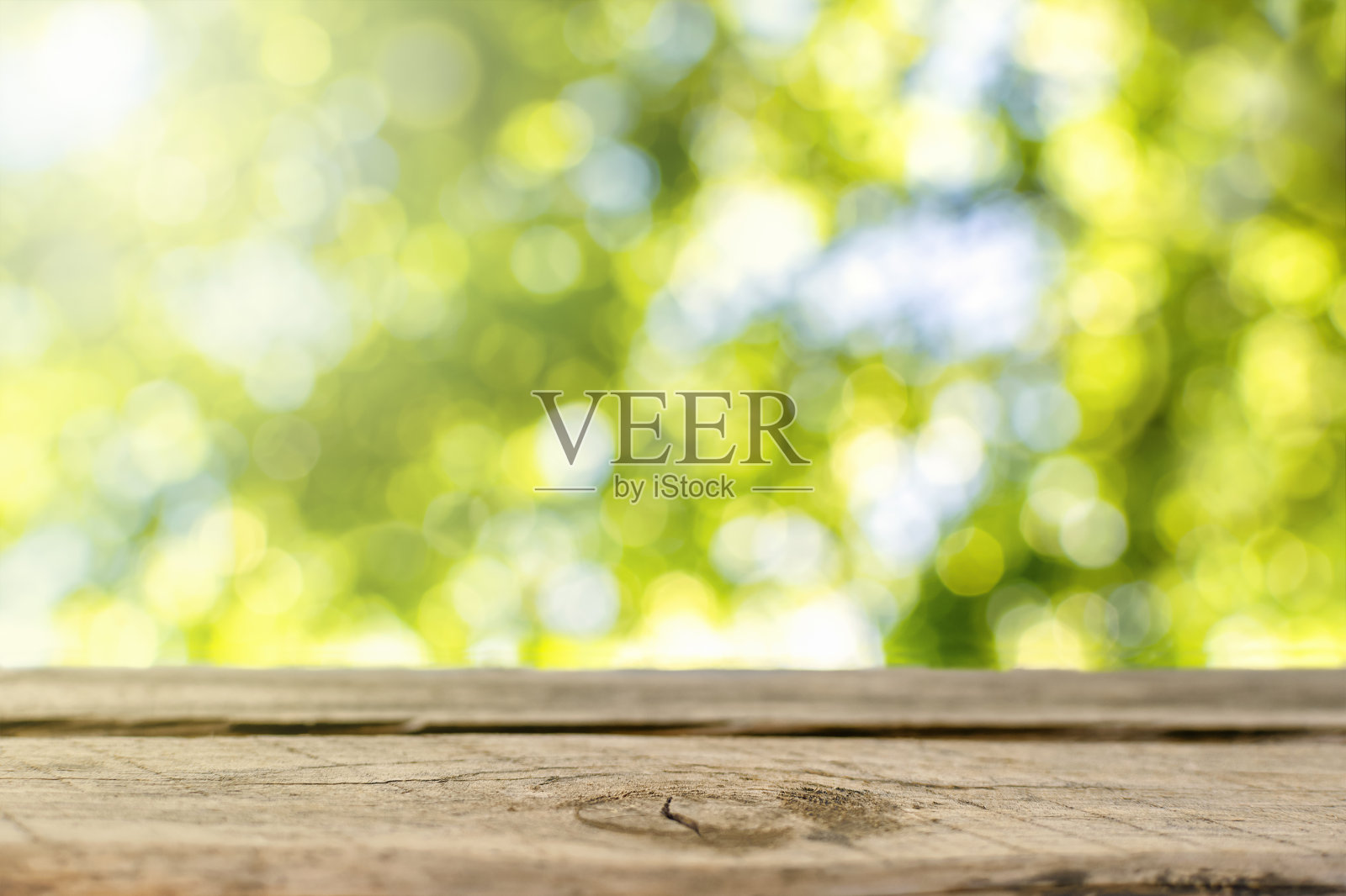 木质桌面上模糊抽象的绿色背景郁郁葱葱的树叶和阳光。为产品展示或视觉布局设计的空台柜台照片摄影图片