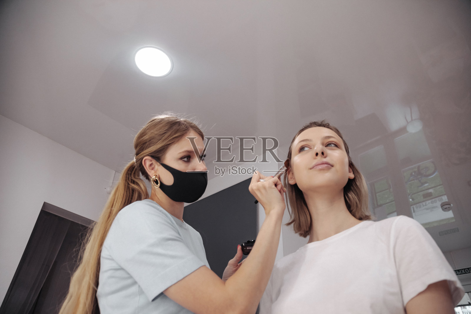 女化妆师在美容院为可爱的年轻女子化妆照片摄影图片