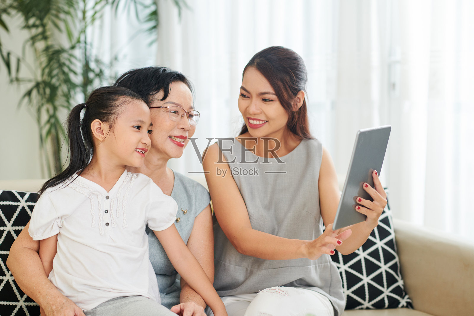 一名妇女向母亲和女儿展示平板电脑上的照片照片摄影图片