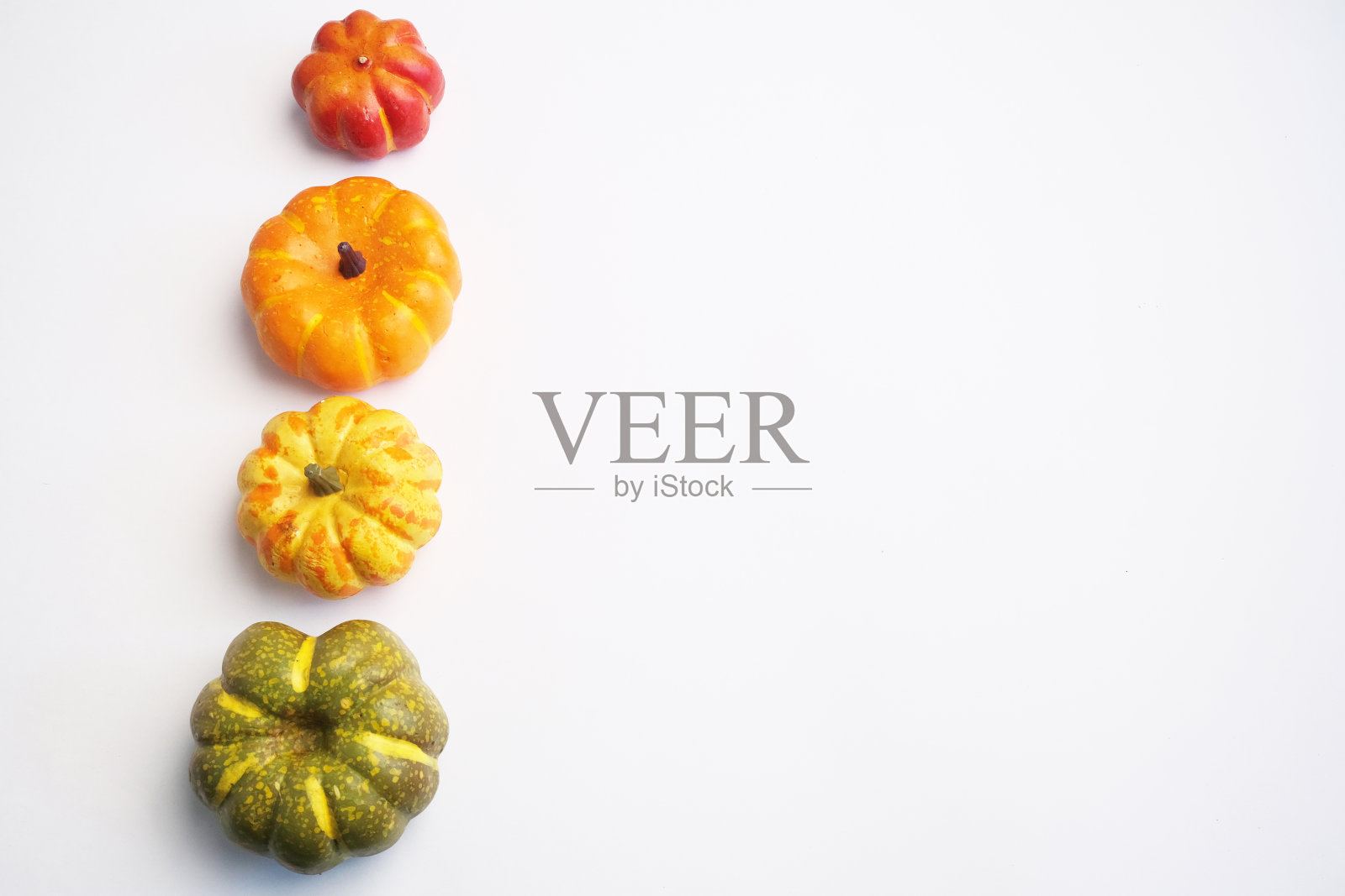 橙色,黄色,绿色的南瓜放在白色的背景上。照片摄影图片