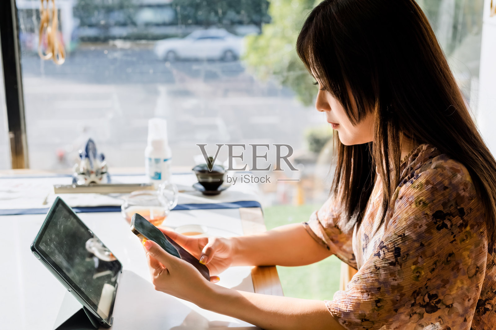 亚洲年轻女子在茶馆喝茶时使用智能手机照片摄影图片