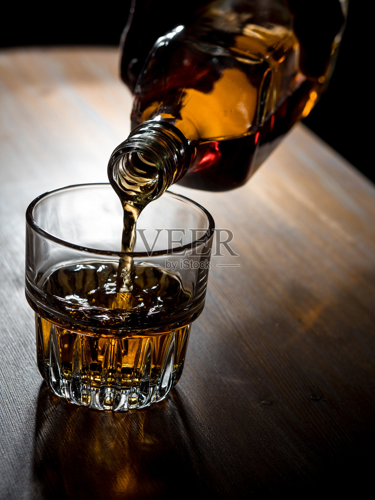 将威士忌倒入玻璃杯中照片摄影图片