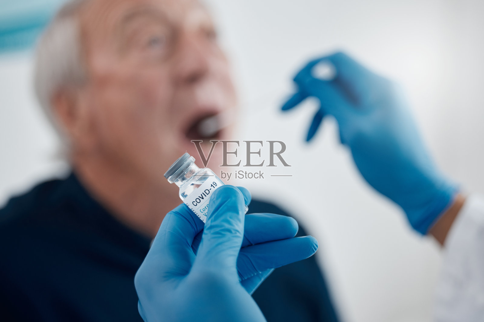 一名无法辨认的医生为一名老年男性病人检测冠状病毒照片摄影图片