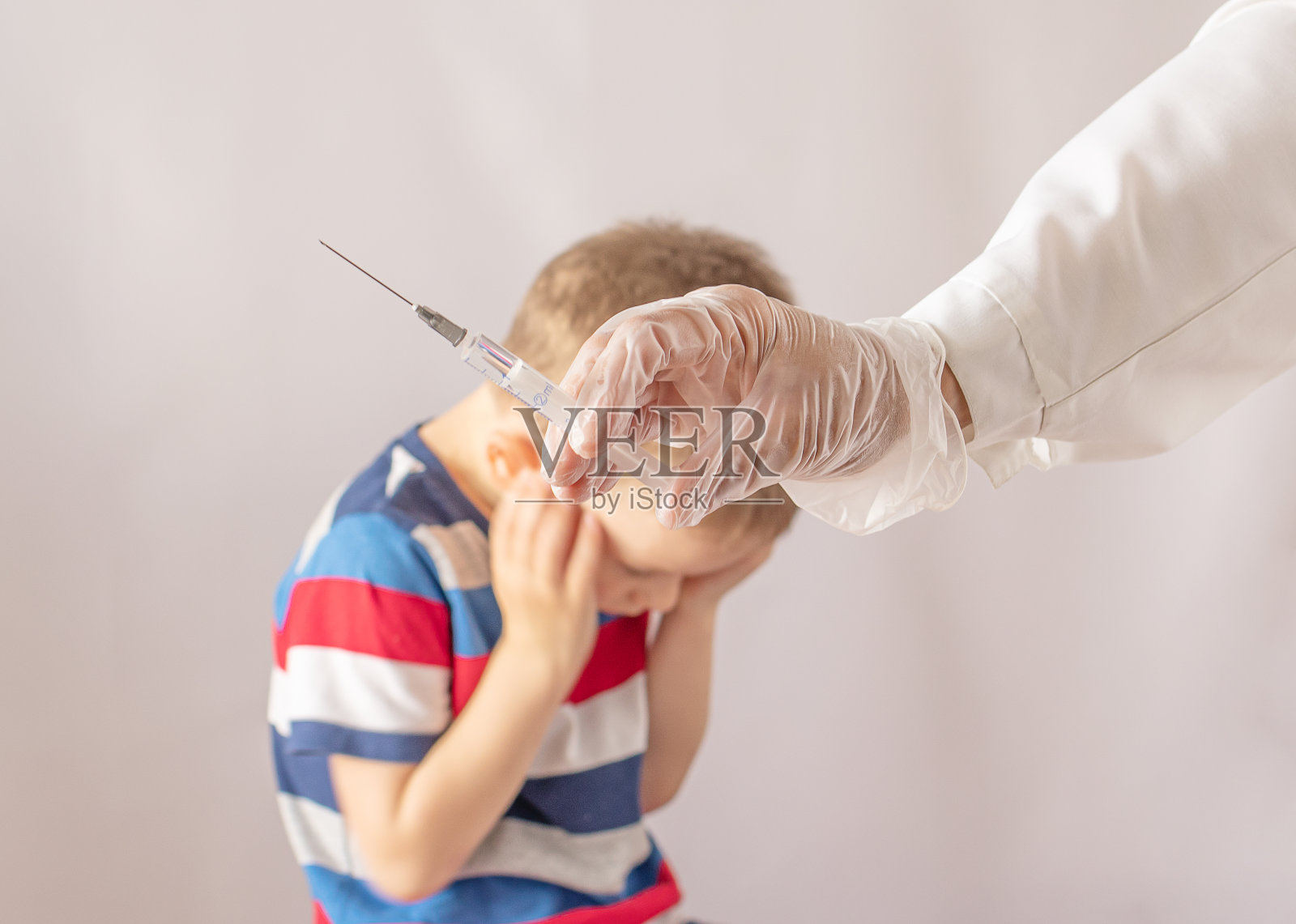 医生拿着注射器注射疫苗。男孩害怕。害怕打针照片摄影图片