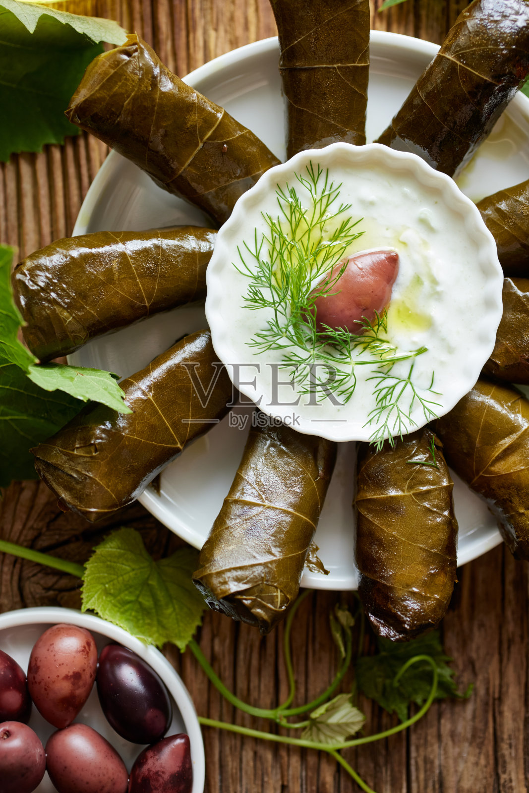 这是一种传统的食物,用酿好的葡萄叶子和酸奶黄瓜酱放在木桌上照片摄影图片