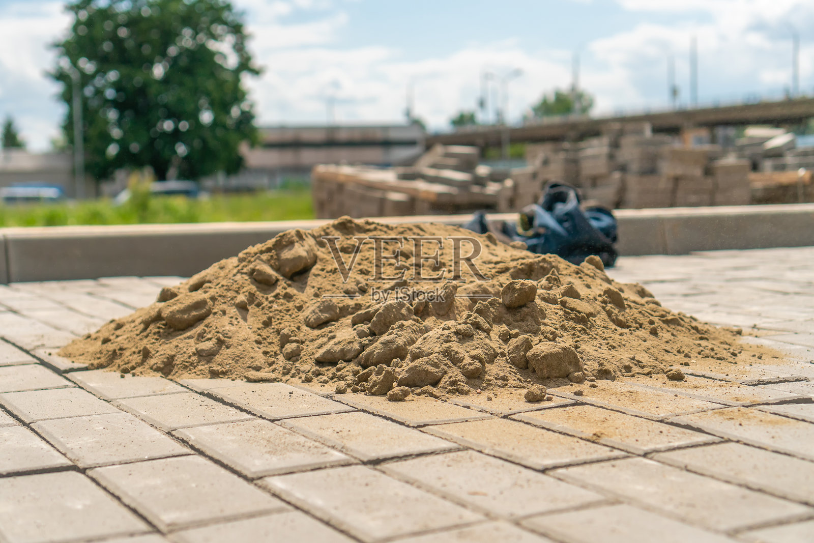 一堆沙子的特写镜头躺在新的人行道上,以密封铺路板之间的接缝。铺路板的铺设照片摄影图片