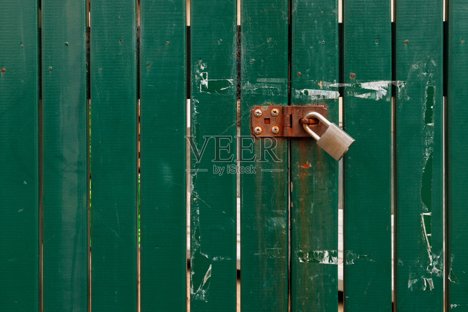 绿色木门上旧的生锈的金属挂锁照片摄影图片