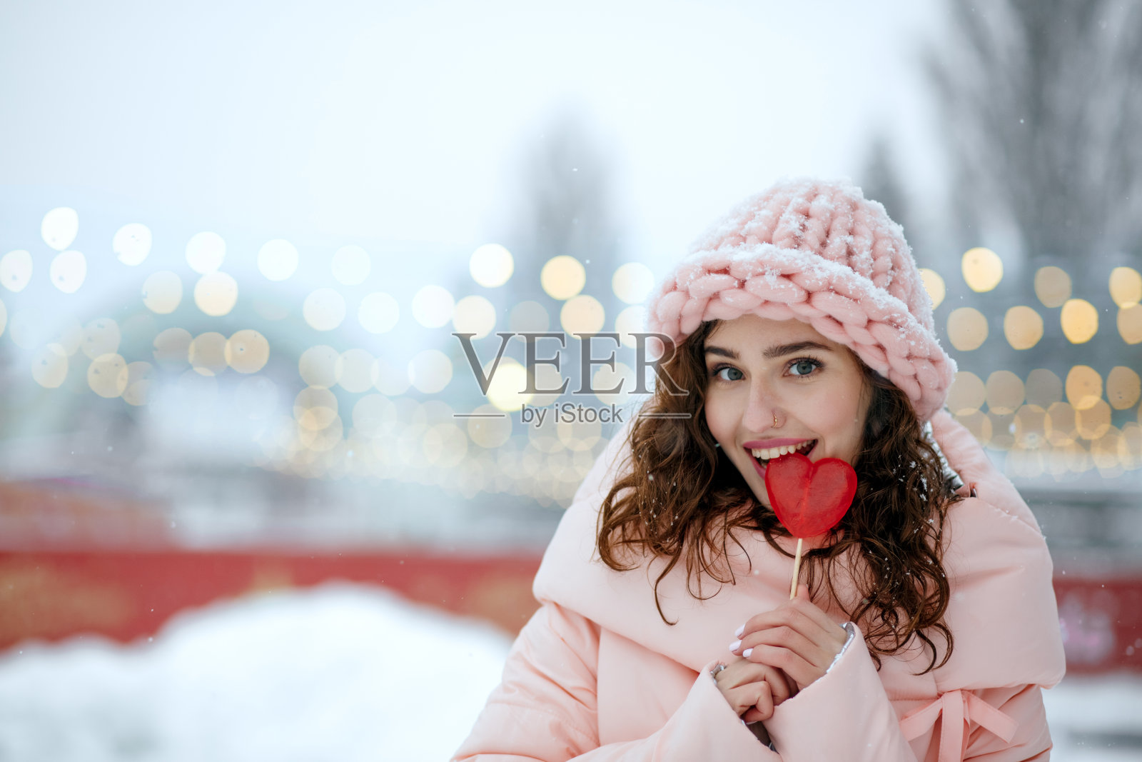 可爱的女人咬着心形棒棒糖照片摄影图片