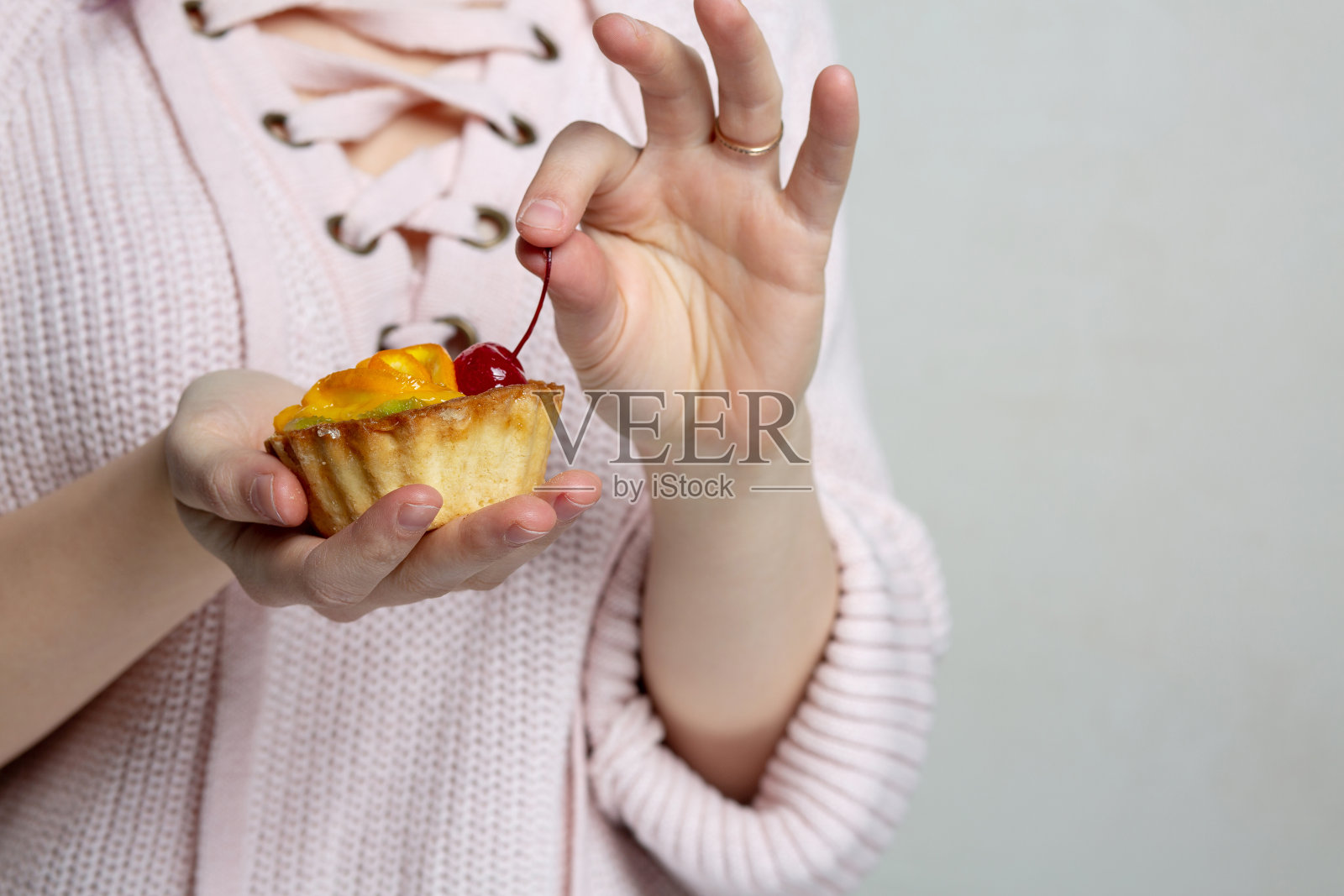 女人手里拿着美味的草莓和橘子纸杯蛋糕。空的空间照片摄影图片