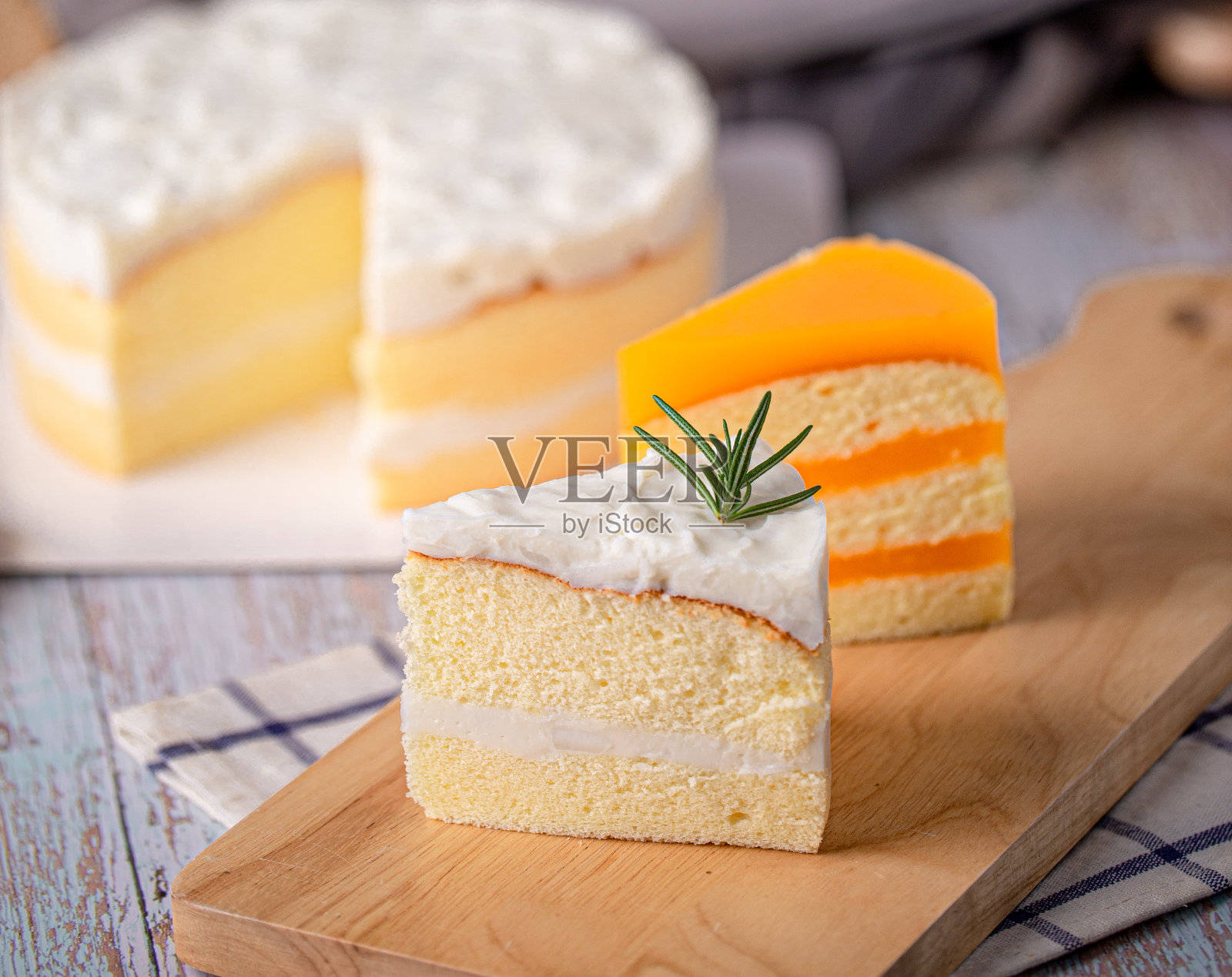 一块自制的椰子蛋糕和橘子蛋糕放在木板上,照片摄影图片