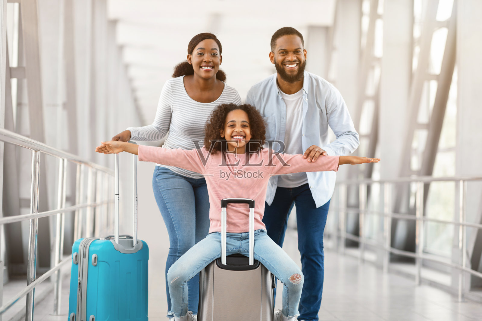 快乐的黑人父母带着女儿,站在机场照片摄影图片