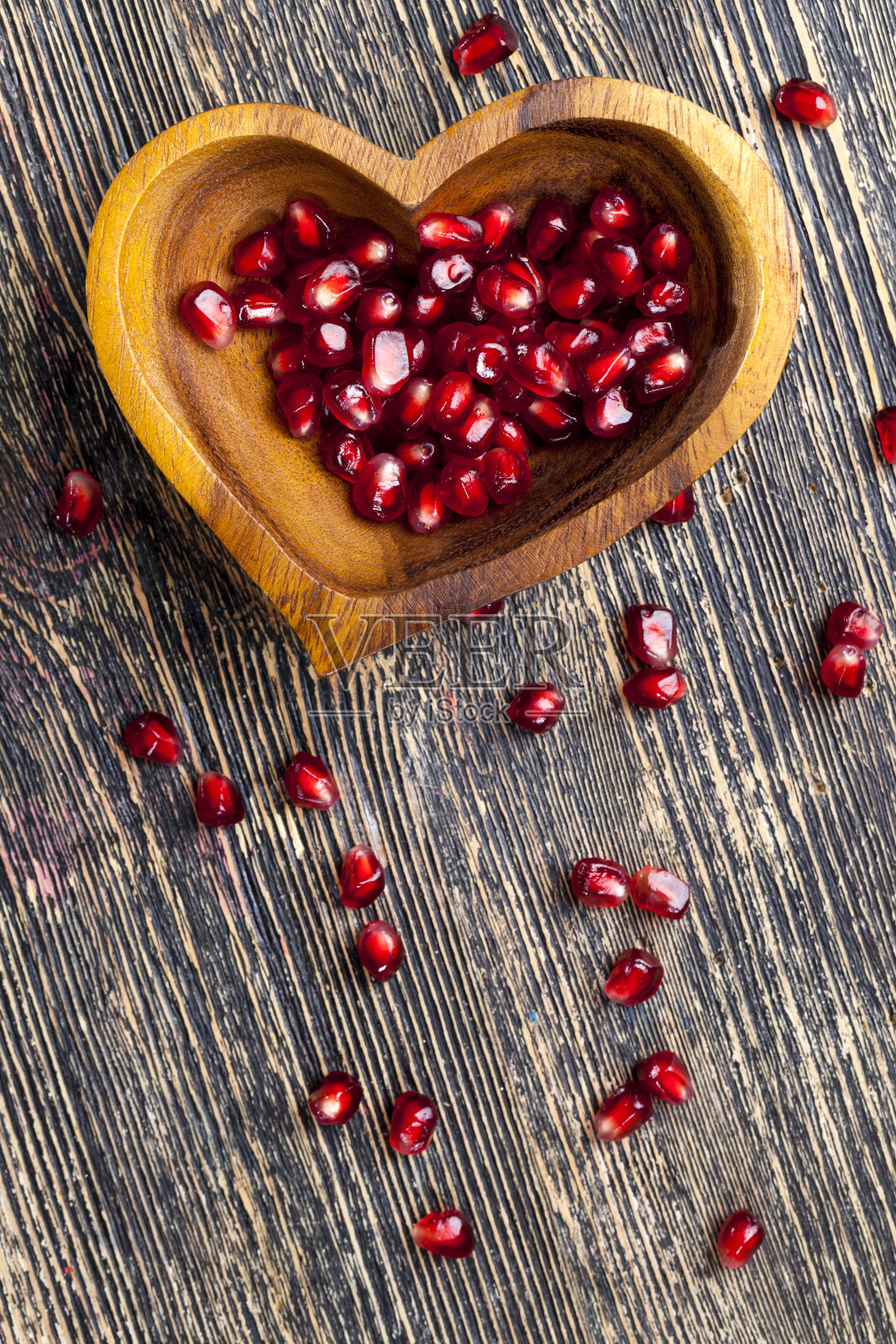 新鲜的石榴籽放在一个心形的碗里照片摄影图片