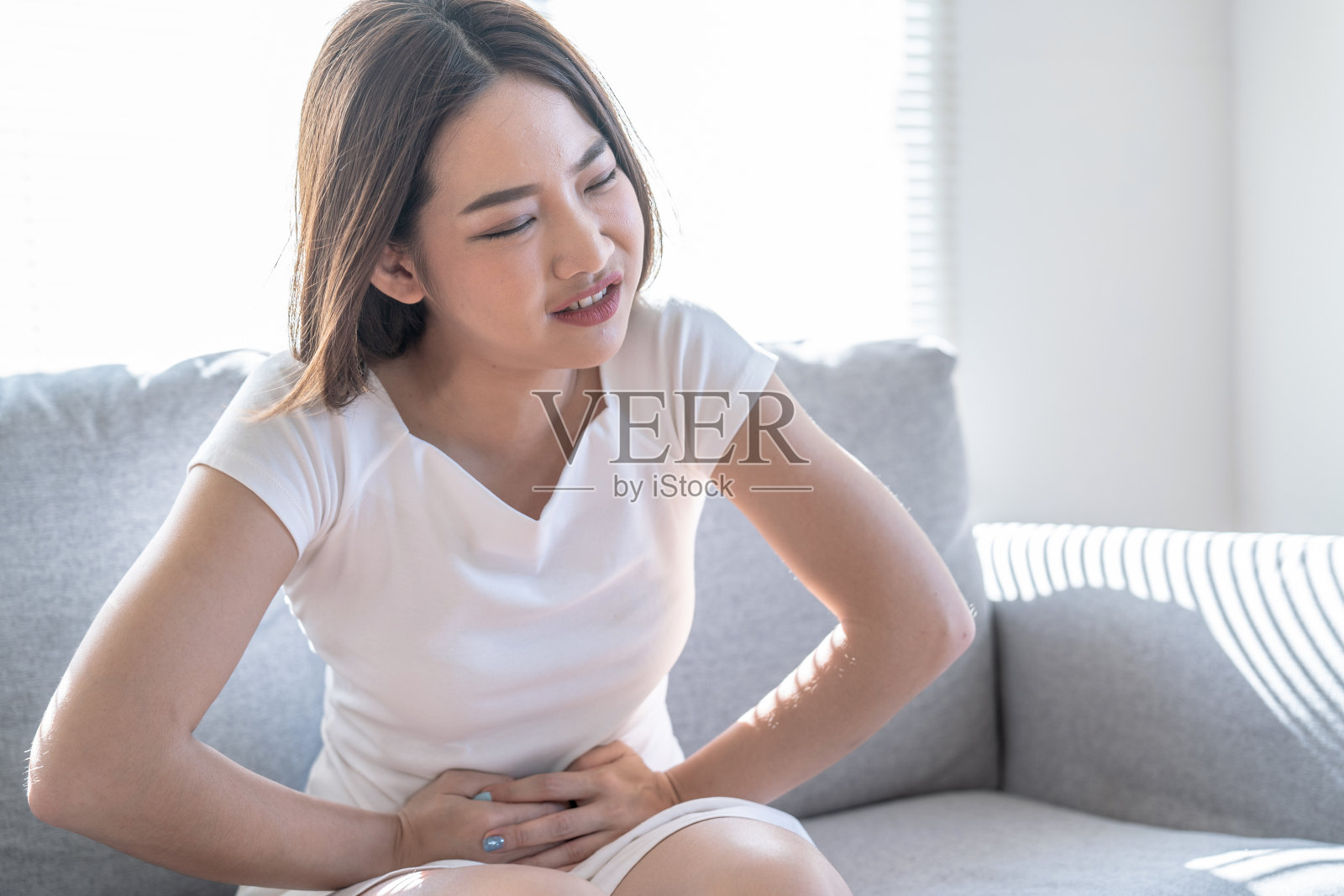 亚洲女性正遭受严重的腹痛,经期腹痛,反流,胃炎,阑尾炎疼痛。照片摄影图片