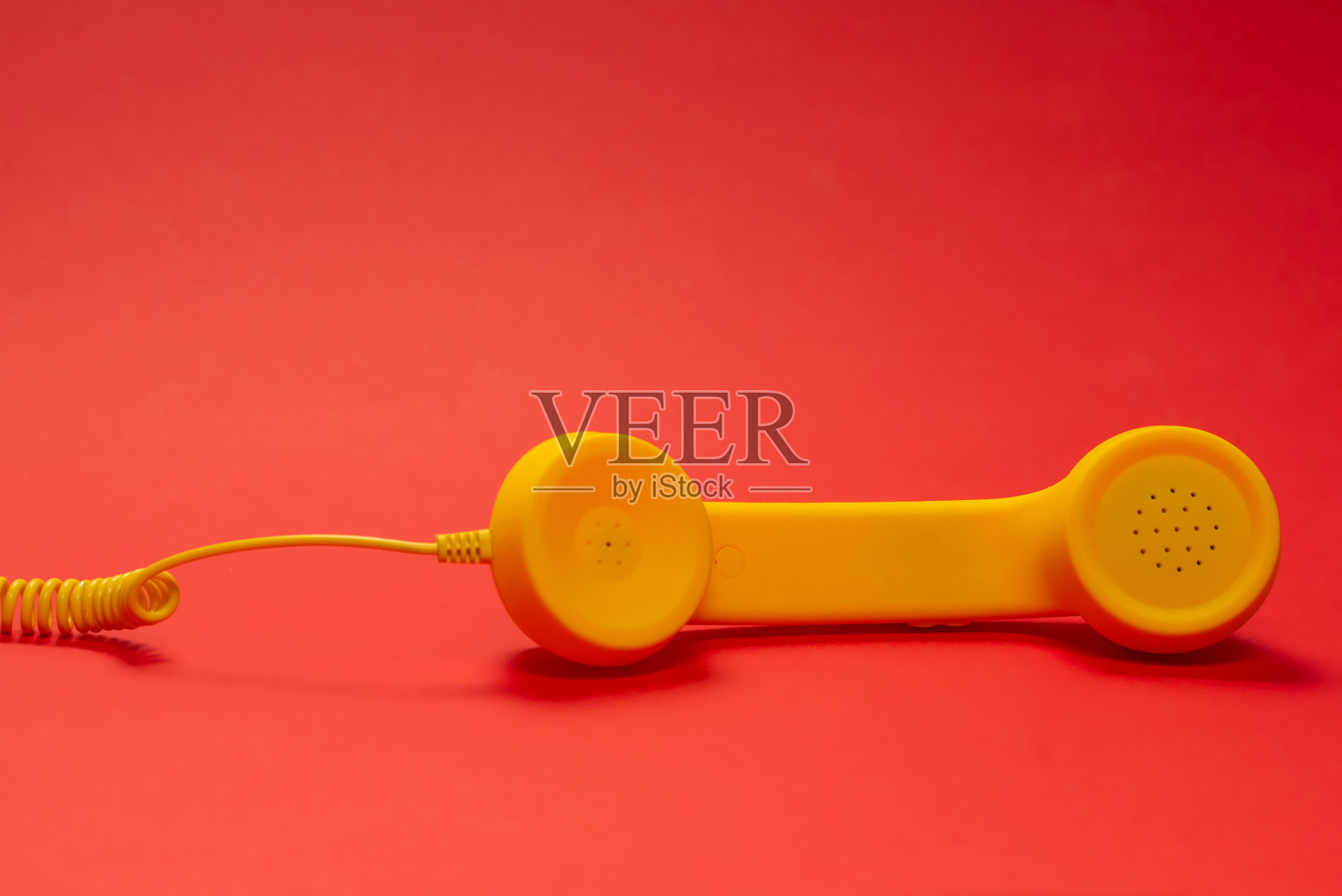 红色背景上的黄色手机。副本的空间。照片摄影图片