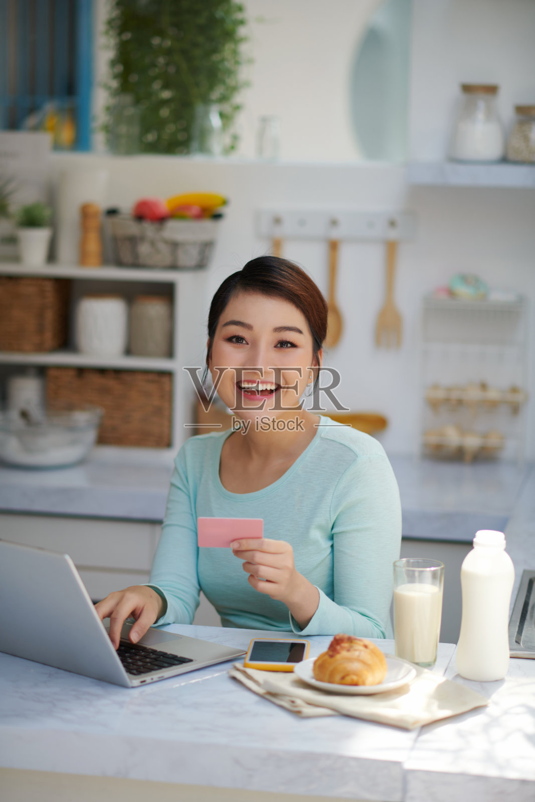 美丽惊喜和成功的女人持有信用卡,并通过塑料卡进行在线支付照片摄影图片