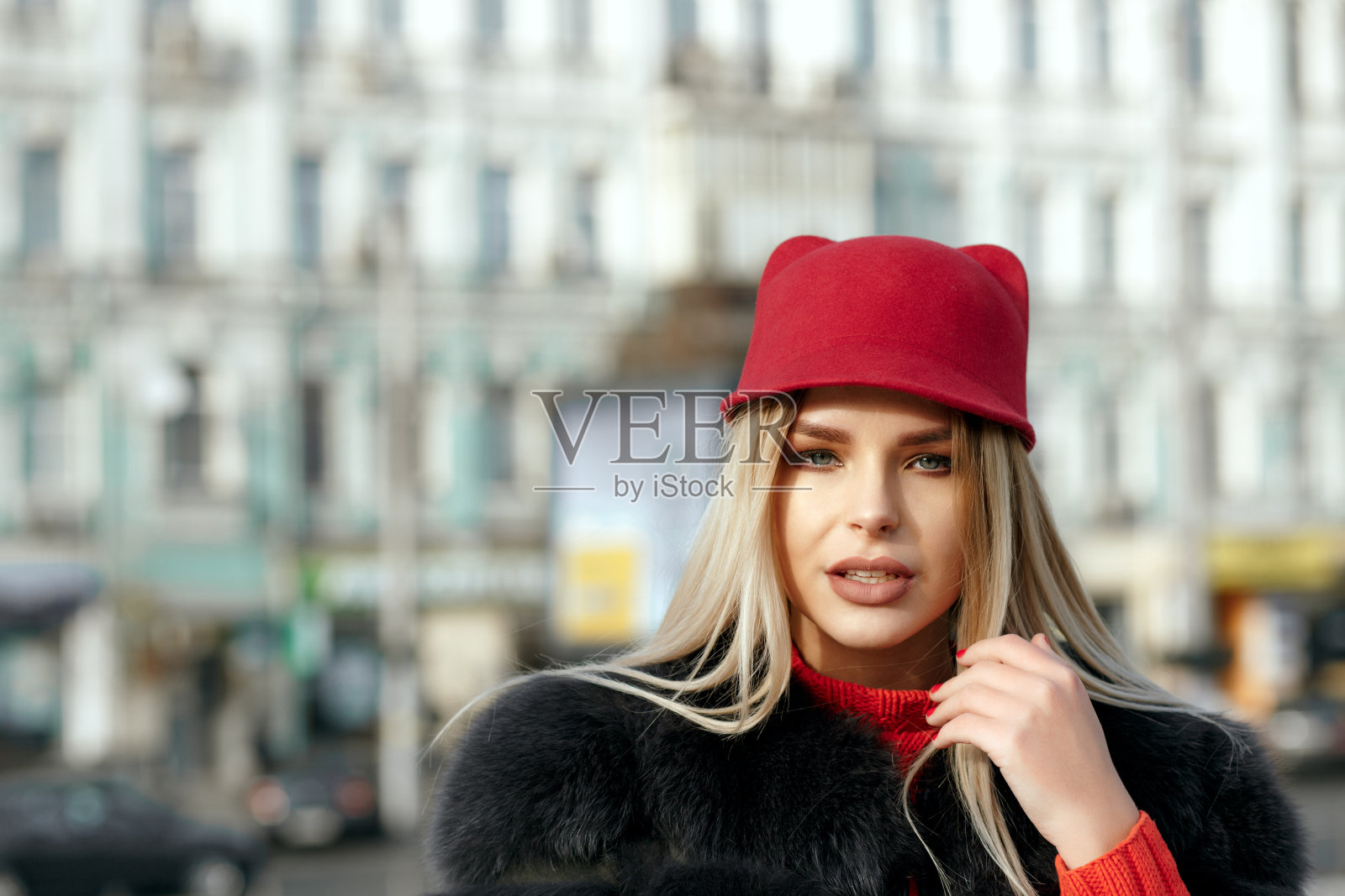 户外的时尚女性肖像戴着时尚的红帽和针织围巾。空的空间照片摄影图片