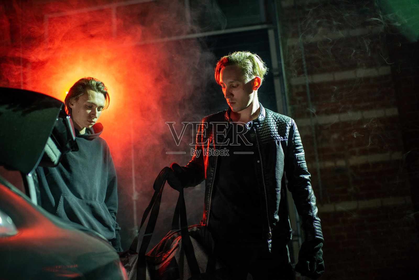 两个家伙在黑色的手提包里藏着偷来的东西照片摄影图片