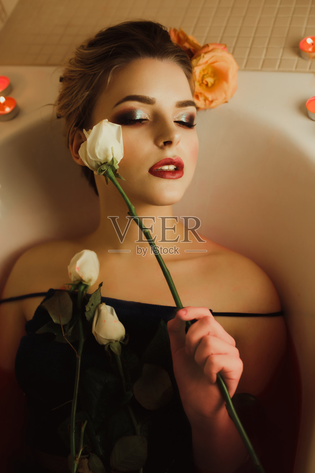 时尚肖像美丽的年轻女子与闭上眼睛抱着白玫瑰在她的眼睛附近照片摄影图片