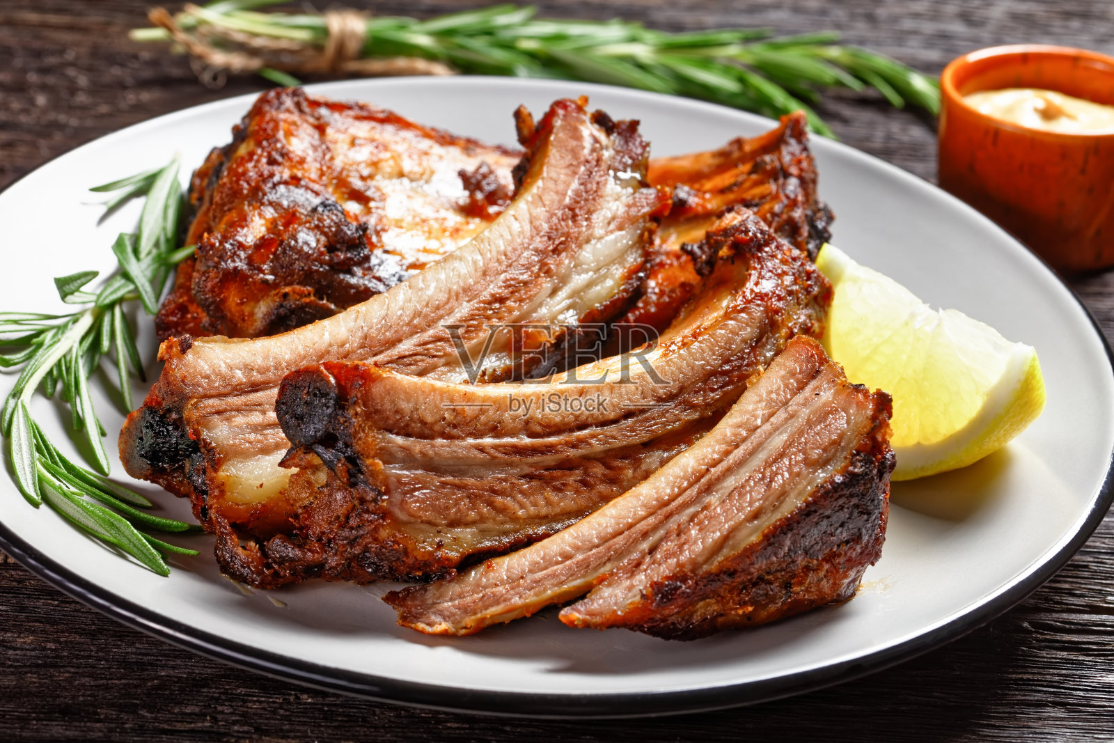 深色木桌上的烤排骨配上柠檬和迷迭香,从上面水平观看,特写照片摄影图片