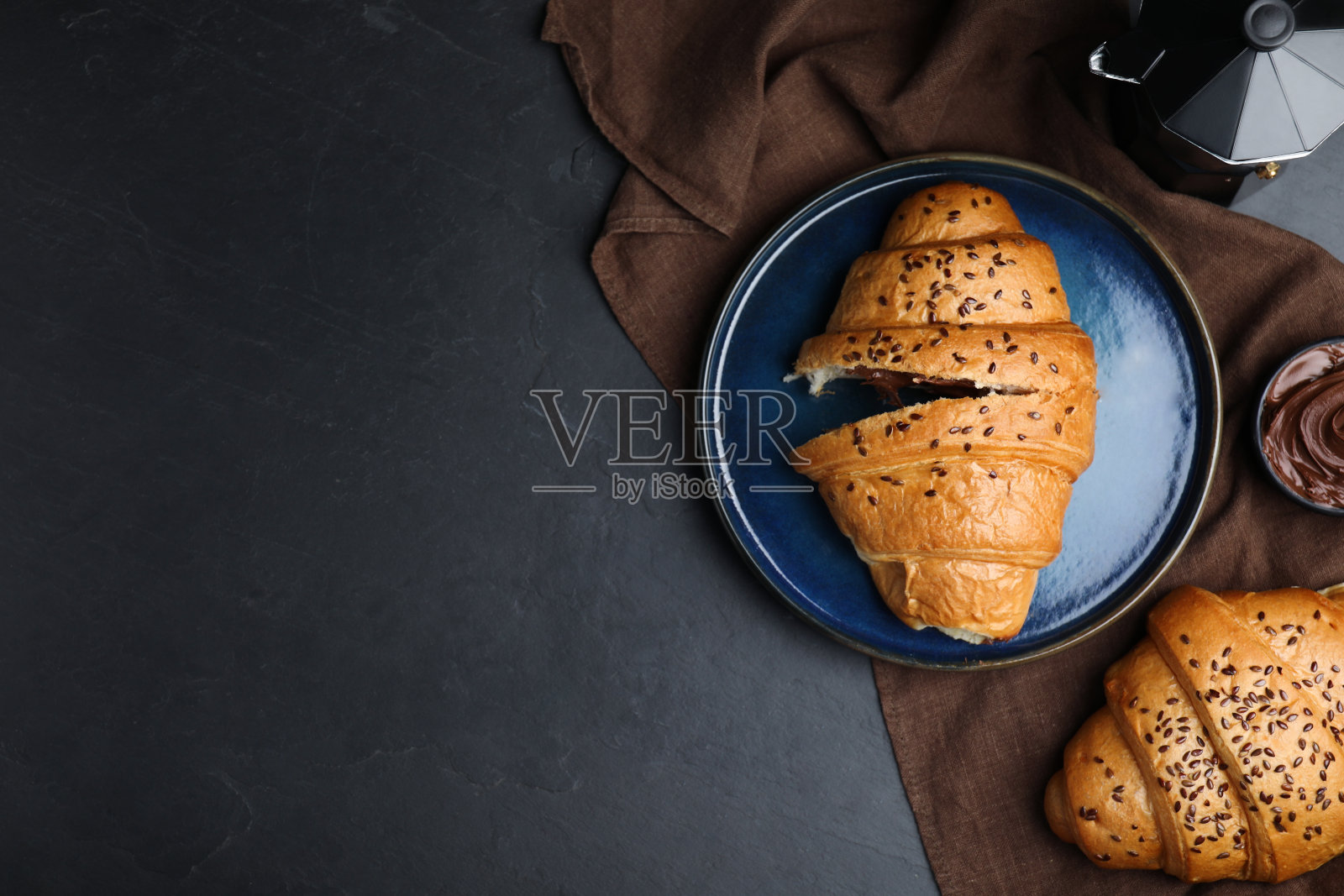 平铺构图与美味的羊角面包在黑色的桌子上。空间的文本照片摄影图片