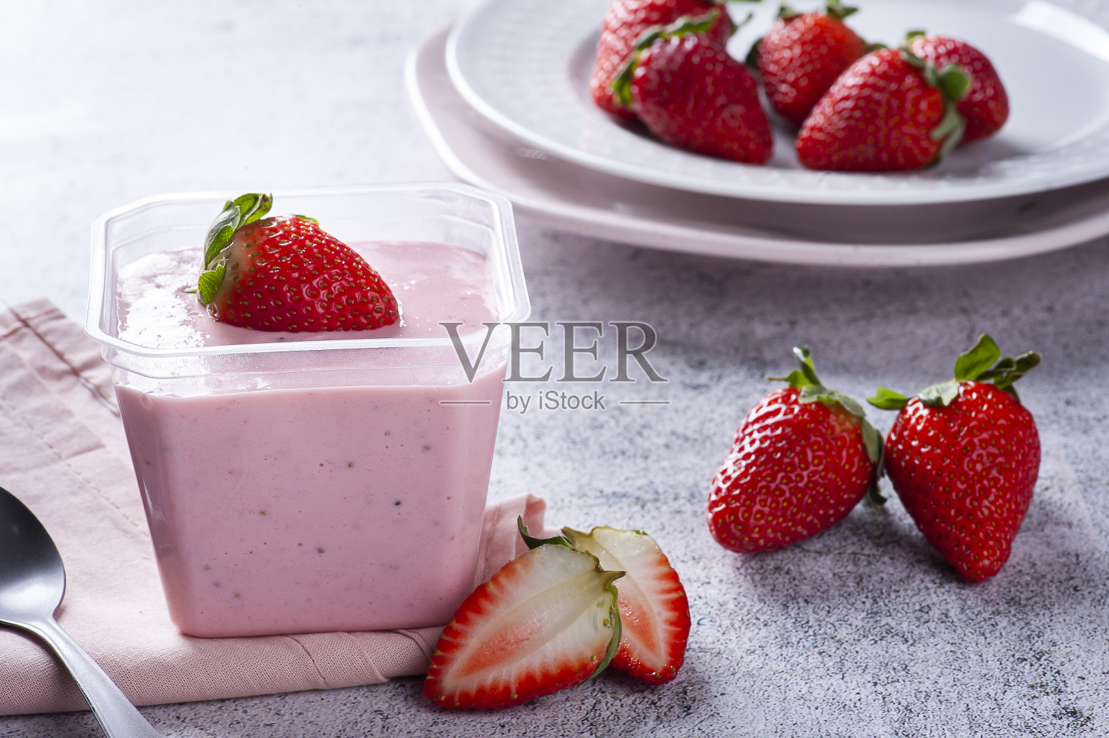 美味的草莓慕斯在一个塑料杯与新鲜的草莓交付。照片摄影图片