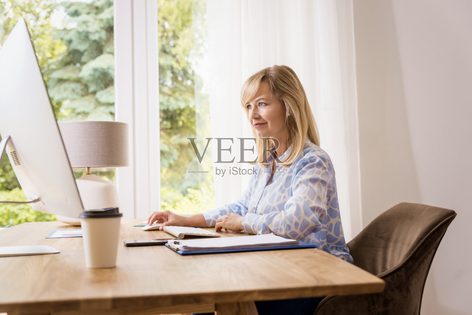 迷人的金发女人在家里用电脑工作照片摄影图片